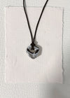 silver knot circle shaped pendant on a black cord against a textured white background