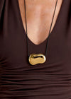 Gold necklace with a unique pendant on a brown garment