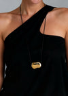 Person wearing a black one-shoulder dress with a gold necklace
