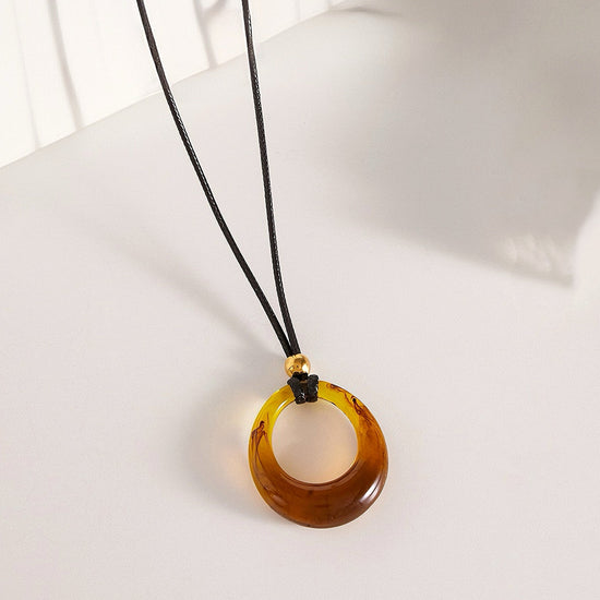 Amber necklace with a black cord on a white surface