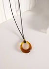 Amber necklace with a black cord on a white surface