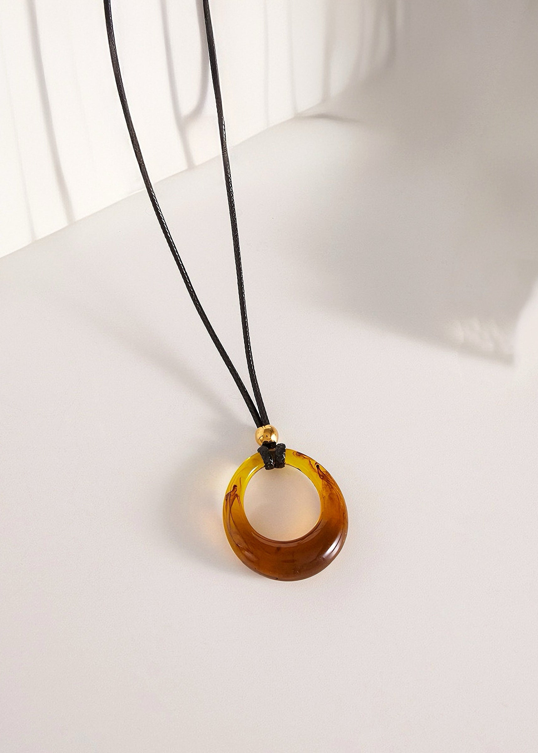 Amber necklace with a black cord on a white surface