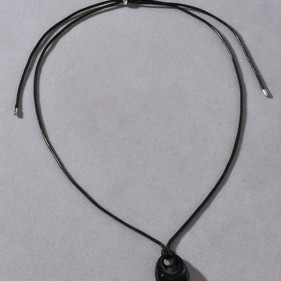 Black necklace with a oval pendant on a gray background