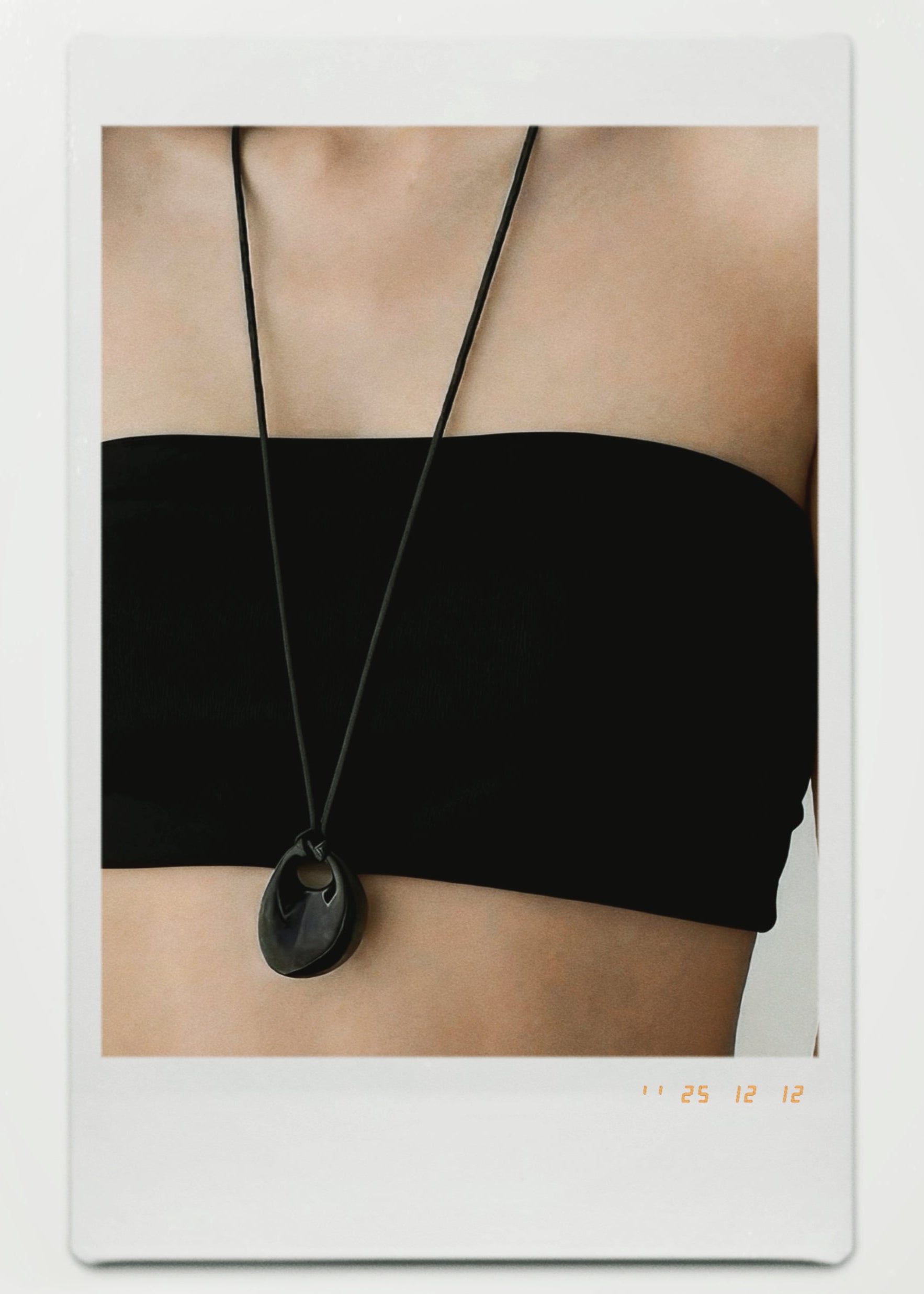 Black necklace with a pendant on a person wearing a black top.