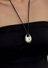 Black necklace with a pendant on a person wearing a black top.