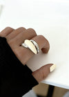 Hand wearing a silver cream ring on a white surface