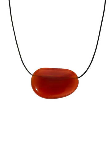Black cord necklace with a large red agate pendant on a white background